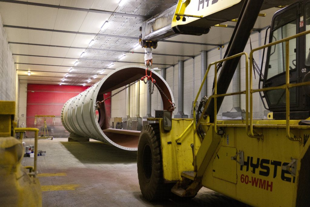 Hyster 60-WMH gaffeltruck flytter en malet cylindrisk sektion gennem hallen